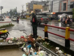 Babinsa Sigap Bersihkan Sampah di Tengah Hujan, Cegah Luapan Air ke Permukiman Warga